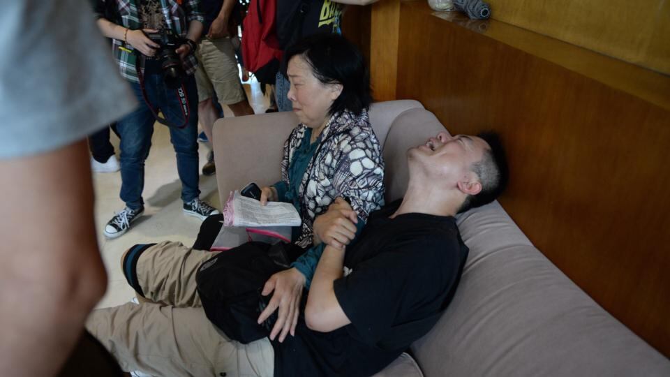 A man, accompanied by his aunt, grieves for his missing parents outside a closed travel agency that participated in organising the  Yangtze River tour. Photograph: EPA