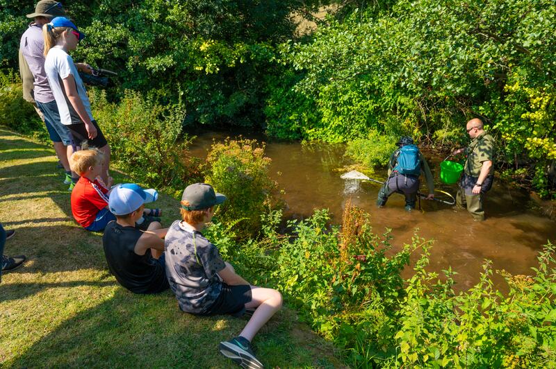 Children sit on the bank waiting to see what the experts fish out of the Ahare River. Photograph: Pedro Souza