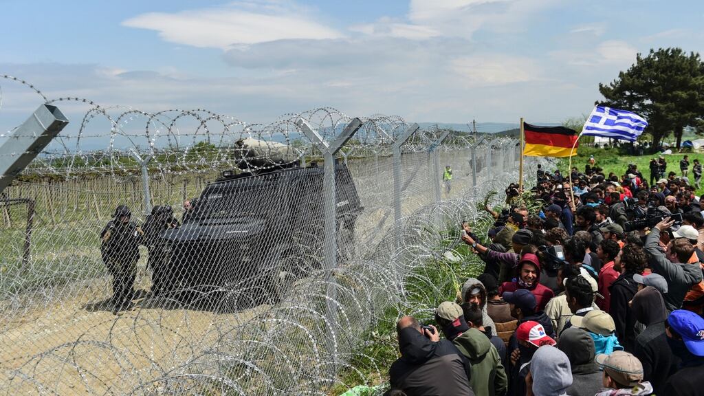 Refugees and migrants face Macedonian soldiers at the border fence with Greece on April 11, 2016. BULENT KILIC/AFP/Getty Images