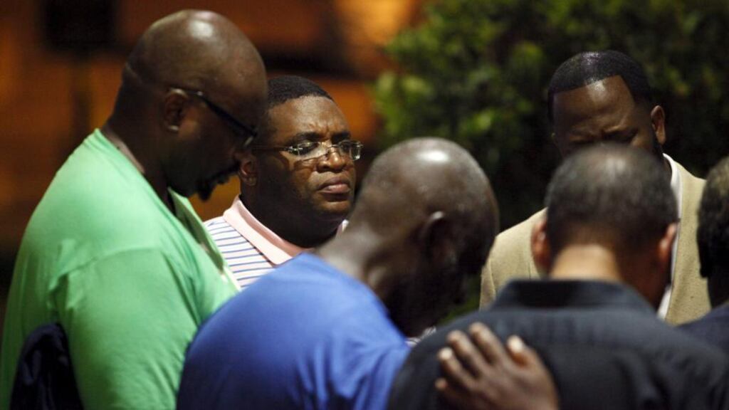 A small prayer circle forms near the scene of the shooting at in Charleston, South Carolina, on Wednesday. “America does not have a monopoly on racism. But what makes its racism so lethal is the ease with which people can acquire guns.” Photograph: Randall Hill/Reuters