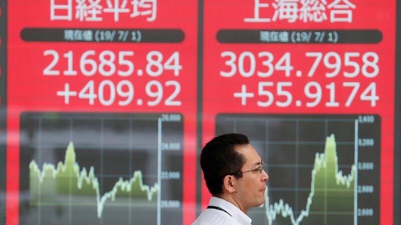 A man walks past an electric screen showing Japan's Nikkei and Shanghai Stock Exchange markets' indices outside a brokerage in Tokyo, Japan, July 1, 2019. REUTERS/Issei Kato