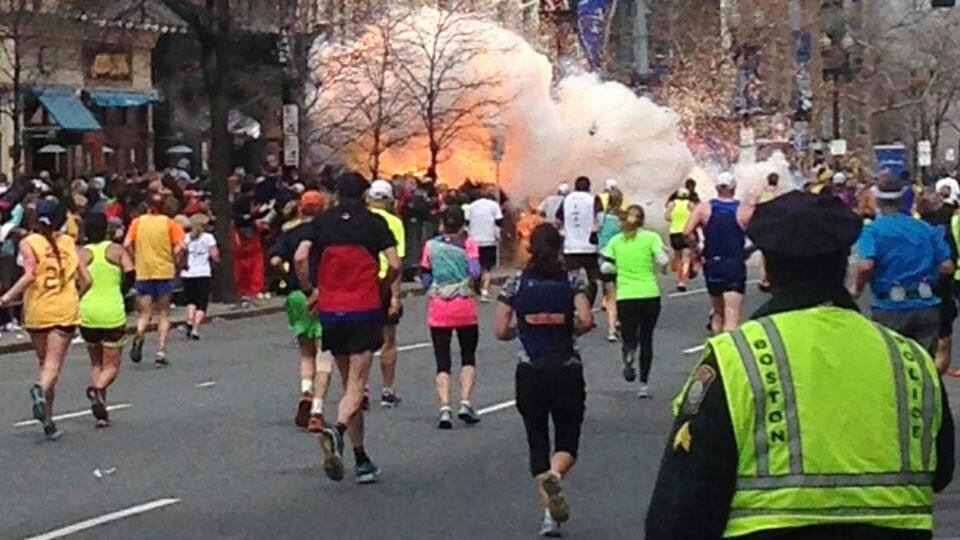 Runners continue to run towards the finish line of the Boston Marathon as an explosion erupts near the finish line of the race. Photograph: Dan Lampariello/Reuters