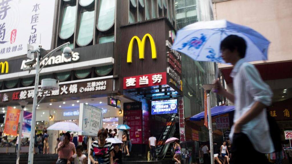 A pedestrian holding an umbrella walks past a McDonald’s  restaurant in the pedestrianised Dongmen area of Shenzhen, China, yesterday. McDonald’s is  working to resume sales beef and chicken in China this week after a supplier was accused of repackaging old meat. The company said the situation is hurting its results in Asia. Photograph: Brent Lewin/Bloomberg