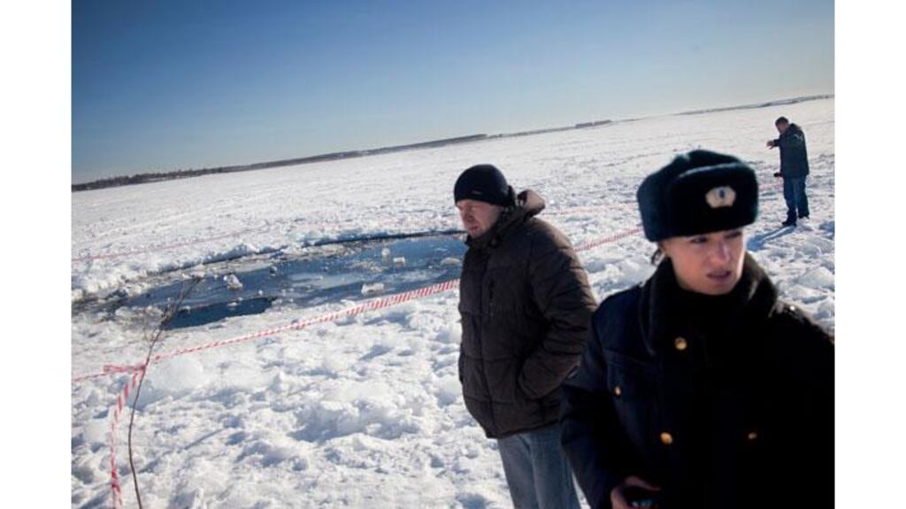 Police and reporters at the site of a 20-foot hole in the ice of Chebarkul Lake, Russia, one of several places where fragments from a meteor were believed to have struck the earth.  Photograph: Ben Solomon/The New York Times