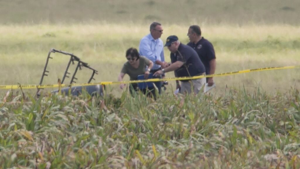 The partial frame of a hot air balloon is visible above a crop field as investigators comb the wreckage of a crash near Lockhart, about 48 km south of Austin, Texas on Saturday. Photograph: Ralph Barrera/Austin American-Statesman via AP