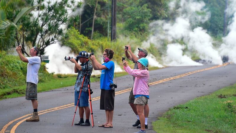 People take photos of lava as steam rises from a fissure in Leilani Estates subdivision on Hawaii’s Big Island. Photograph: Frederic J Brown/AFP/Getty Images