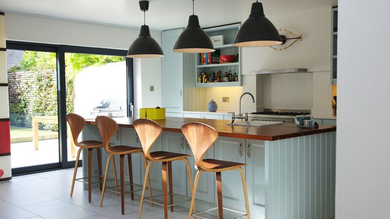 The painted in-frame kitchen features pendant lighting from Industry, a fruit bowl by Universal Positivo, a George Nelson-style clock, and barstools that are replicas of the Norman Cherner classic. Photograph: Emily Quinn