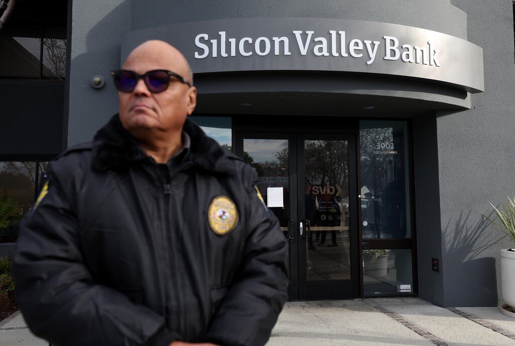 A security guard at Silicon Valley Bank headquarters in Santa Clara, California monitors a line of people outside the office as they try to retrieve their funds from the failed bank. Photograph: Justin Sullivan/Getty Images