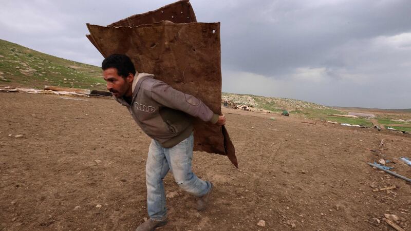 A man gathers material to build a temporary shelter after Israeli forces razed the Bedouin village of Khirbet Humsah. Photograph: Emmanuel Dunand