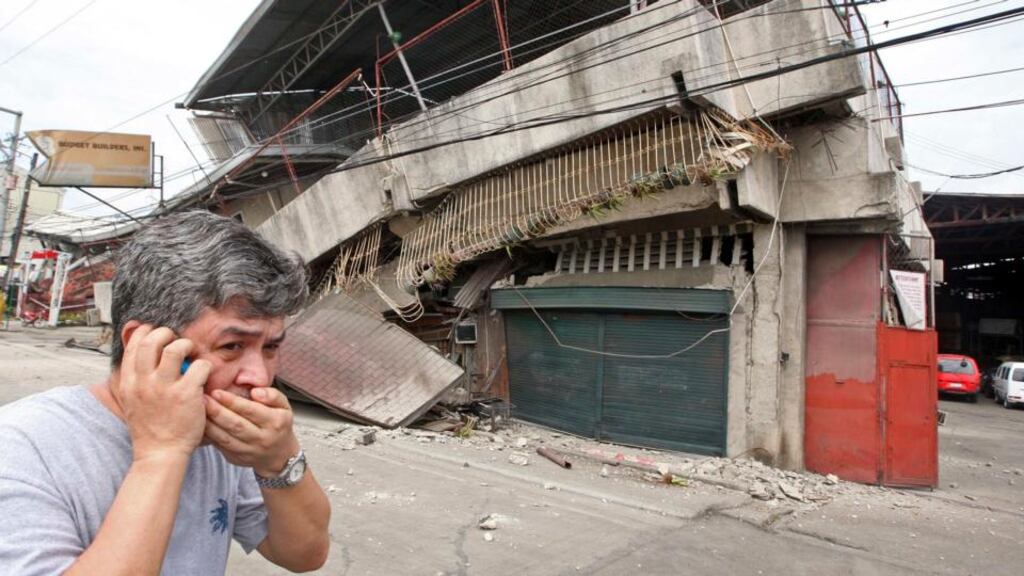 A resident walks past a building that collapsed during an earthquake in Cebu City, central Philippines. A strong earthquake measuring 7.2 struck islands popular with tourists in the Philippines today killing at least 20 people, some while praying in a centuries-old church, officials said. Photograph: Stringer/Reuters