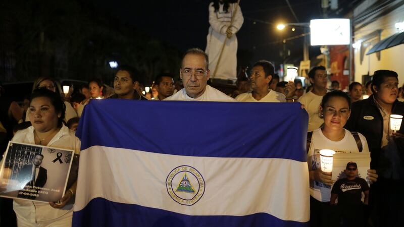 Fr Edwin Roman holds a Nicaraguan flag next to people holding photos of relatives who died in protests during the procession of El Silencio on Holy Thursday in Masaya. Photograph: Inti Ocon/ AFP/ Getty Images