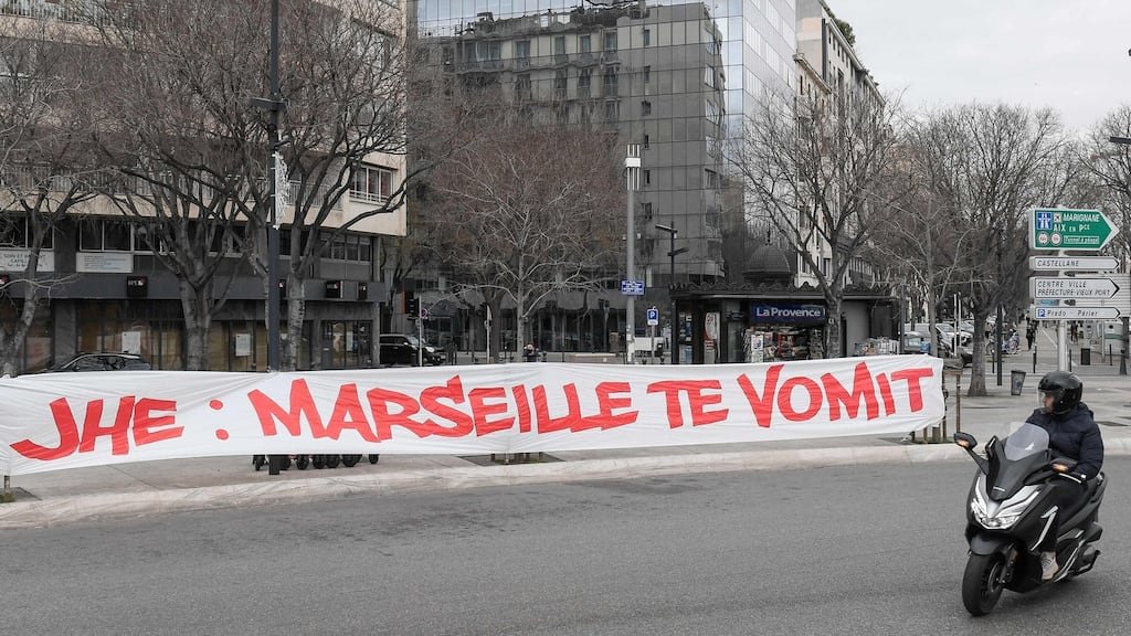 A man on a scooter looks over at a banner hung by Marseille fans against the club’s president Jacques-Henry Eyraud, that reads in French ‘JHE: Marseille vomits you’, a few hours before the Ligue 1 match against Rennes. For several weeks, protests have been organized by OM supporters before the home matches. Photo: Nicolas Tucat/AFP via Getty Images