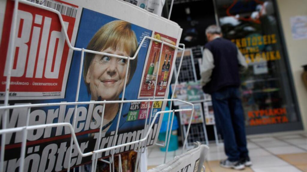 A photograph of German chancellor Angela Merkel looks out from the front page of Bild on a newspaper stand following her election victory, in Corinth, Greece, yesterday. Photograph: Kostas Tsironis/Bloomberg