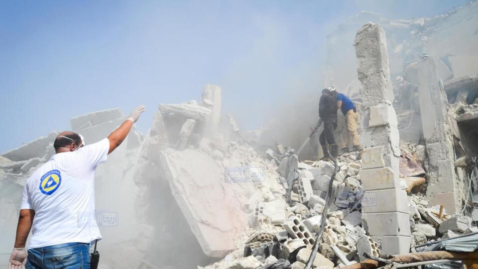 This photo provided by the Syrian anti-government activist group Ariha Today, which has been authenticated, shows Syrian civil defence workers standing on the rubble of a destroyed building that was damaged after a government warplane crashed in the centre of the town of Ariha on Monday. Photograph: Ariha Today via AP.