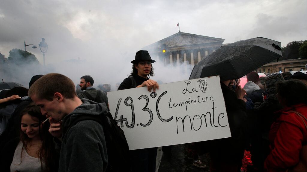 A demonstrator holds a board reading “The temperature rises” during a protest in front of the National Assembly in Paris: Prime minister Manuel Valls pleaded with a socialist group meeting before asking the cabinet to authorise use of article 49.3 of the constitution. Photograph: Christophe Ena/AP