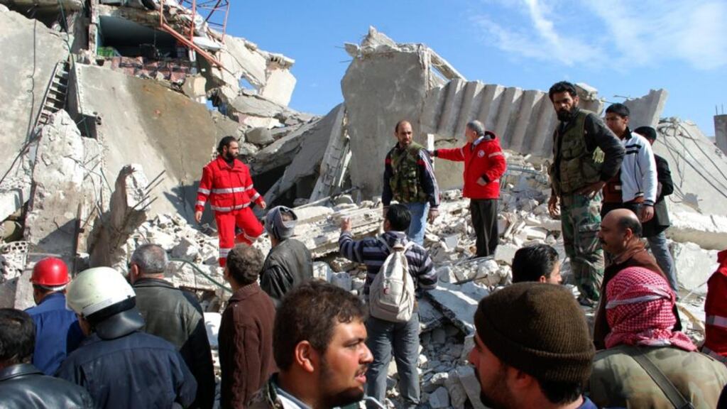 A handout photo released by the official Syrian Arab News Agency (SANA) shows Syrian citizens inspecting the damages at the site that has been rocked by a car bomb explosion in al-Kaffat town, Hama.