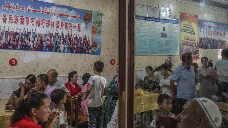 Patrons dine under posters quoting Xi Jinping, reading ‘every ethnic group must tightly bind together like the seeds of a pomegranate’, at a restaurant in Yarkand, in China’s Xinjiang province. Photograph: Gilles Sabrié/New York Times