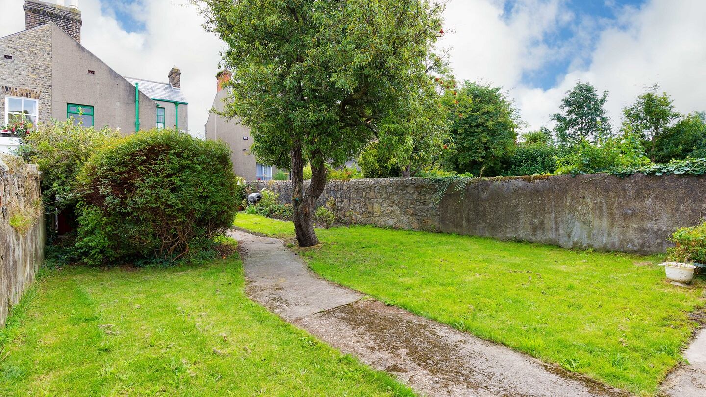 The garden has a long bed of old roses along a granite wall, as well as trees and shrubs.