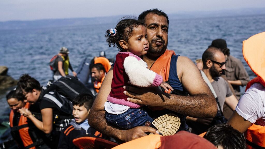 A man carries his child shortly after arriving with other migrants and refugees on the Greek island of Lesbos after crossing the Aegean sea from Turkey, on Sunday. The Greek coastguard said five more migrants including a baby and two boys had died trying to cross the Aegean Sea from neighbouring Turkey. Photograph: Dimitar Dilkoff/AFP/Getty Images
