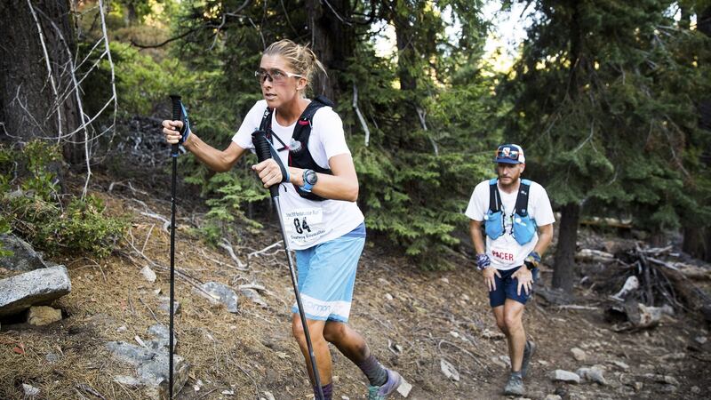 Courtney Dewaulter hikes uphill with her pacer Mike Wilkinson at about 155 miles into the Tahoe 200 ultramarathon in Strawberry, California.