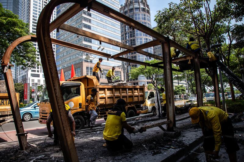 Workers repair a bus stop burnt down by protesters near Jakarta police headquarters on Tuesday. Photograph: Aditya Irawan/Getty