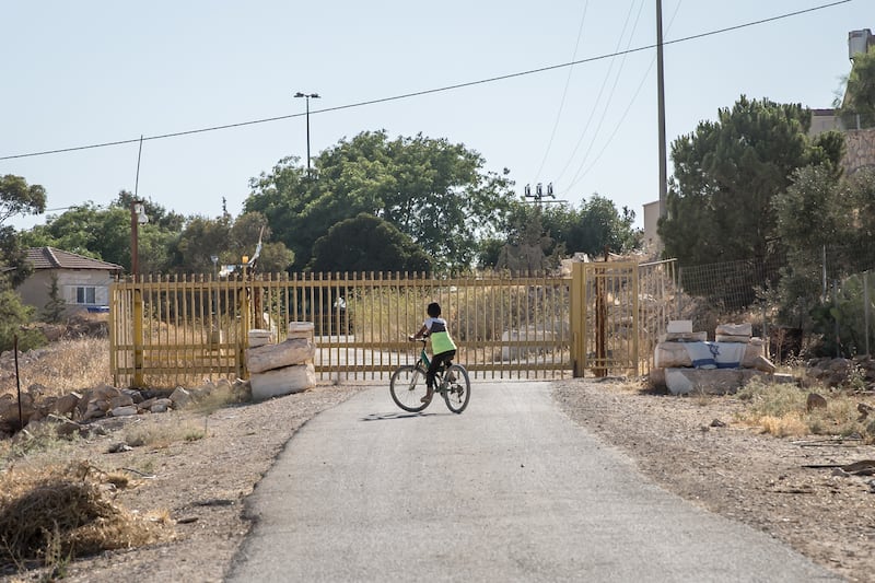 A Palestinian child on a bicycle in the village of Umm al Khair, in front of a gate protecting the nearby Israeli settlement. Photograph: Sally Hayden