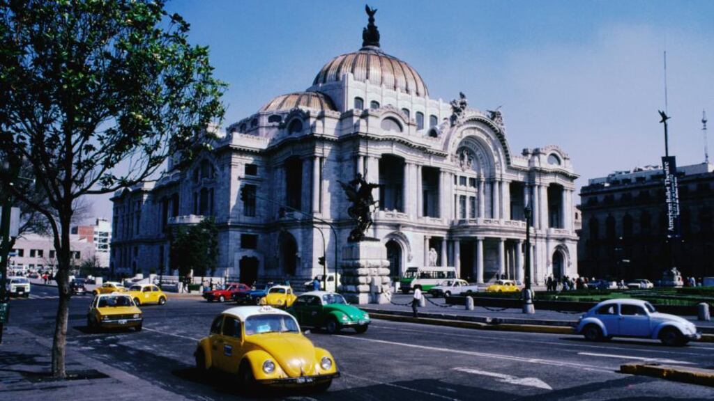 Volkswagon Beetles, still produced in Mexico, cruise by Palacio de Bellas Artes. Photograph: Getty