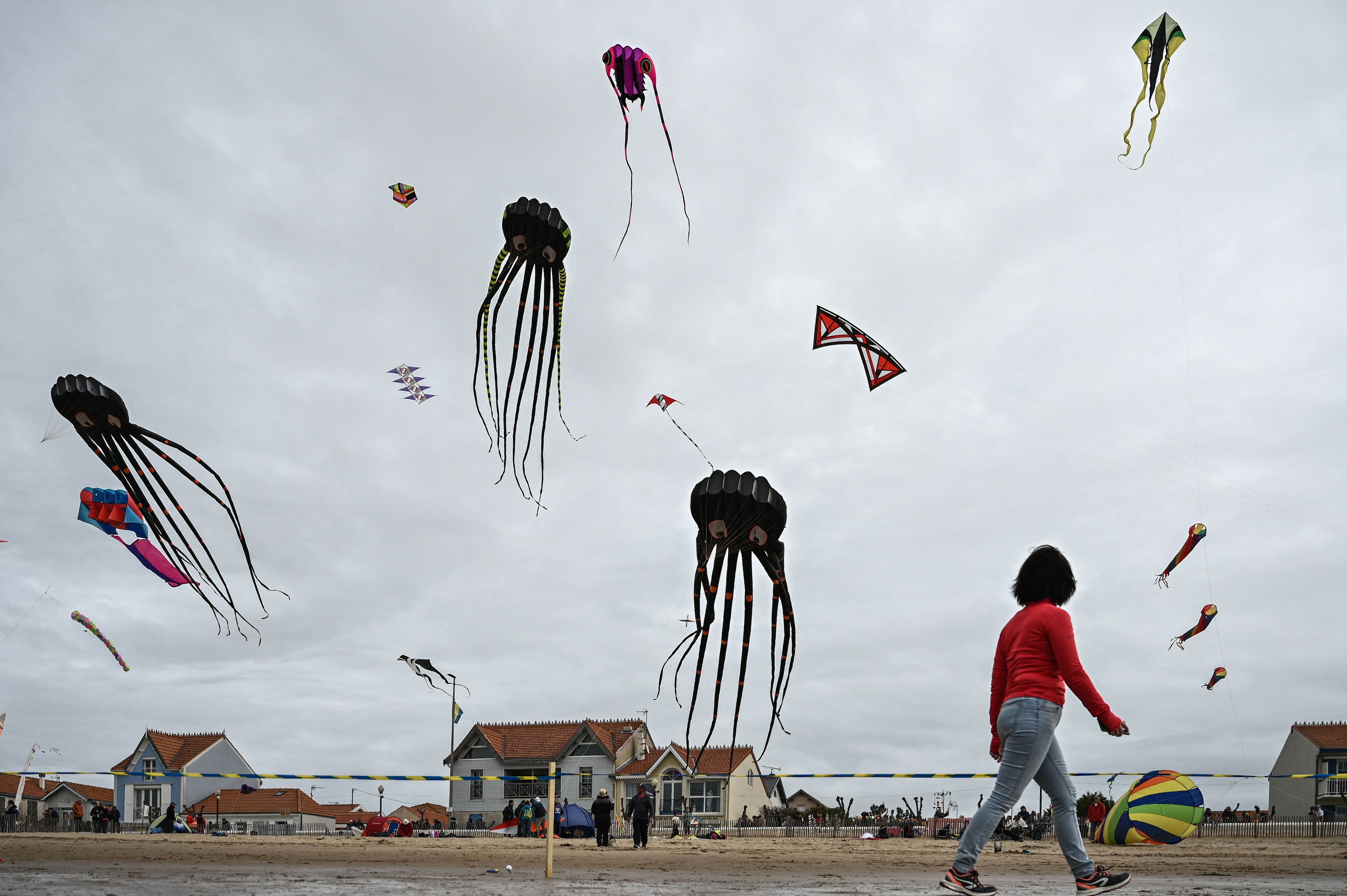 A woman walks past flying kites during the 29th edition of the International Kite and Wind Festival as kite flyers from all over France and abroad gather in Chatelaillon-Plage, south-western France. Photo: Philippe Lopez/AFP