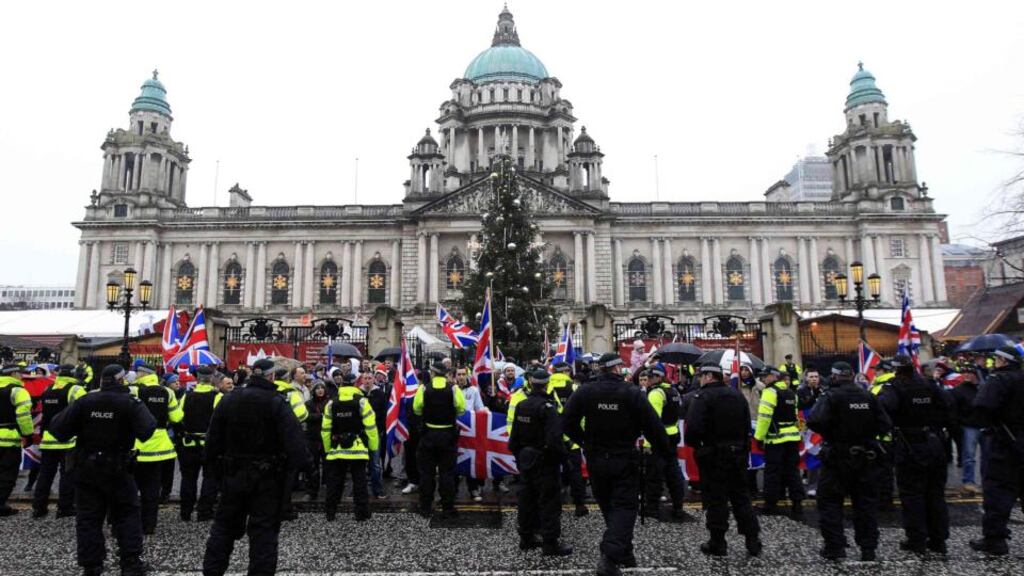 Police in riot gear look on as protesters wave union flags in front of Belfast City Hall in December last year. Anniversary demonstrations have been planned. Photograph: Reuters/Cathal McNaughton