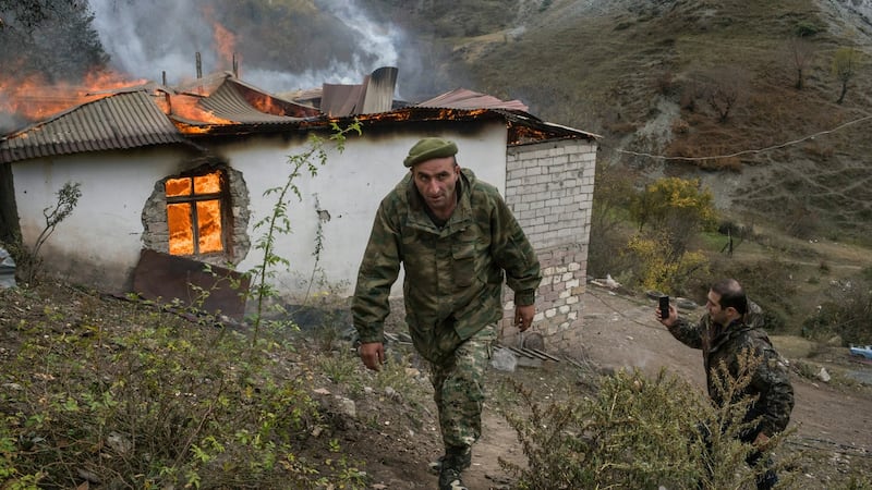 Armenian soldiers walk by a home burning near the Dadivank monastery in the Kelbajar District, before Azeris arrive to take over. Photograph: Mauricio Lima/New York Times