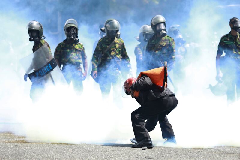A man picks up a tear gas canister to throw it away after police fired it to disperse the protesters in Colombo. Photograph: Amitha Thennakoon/AP