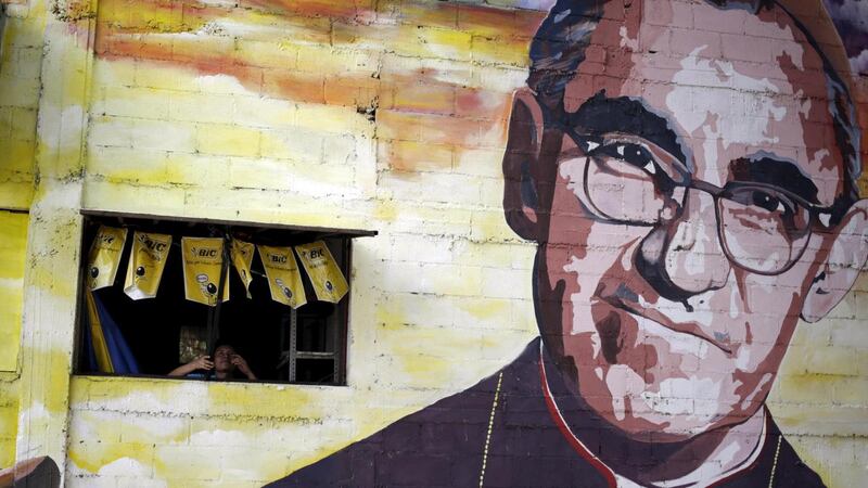 A man closes a window in the wall next to a mural of the late Salvadoran Archbishop Oscar Arnulfo Romero in Panchimalco, on the outskirts of San Salvador. Photograph: Jorge Dan Lopez/Reuters