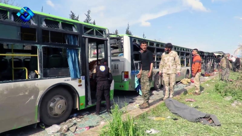 Rebel gunmen stand at the site of a blast that damaged several buses carrying evacuees. Photograph: Thiqa News/AP