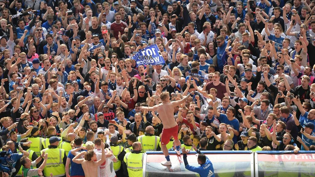 Hamburg’s Lewis Holtby stands on the dugout as he celebrates with the fans after they beat Wolfsburg to stay up. Photo: Clemens Bilan/EPA