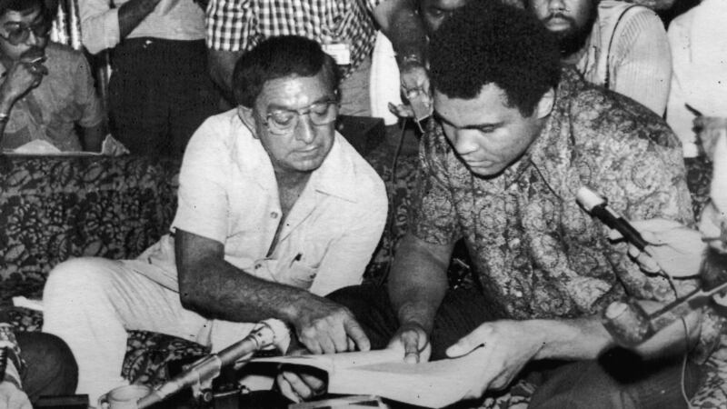 Heavyweight boxing champion Muhammad Ali looks at a book with his manager Angelo Dundee in 1975. Photograph: Evening Standard/Hulton Archive/Getty