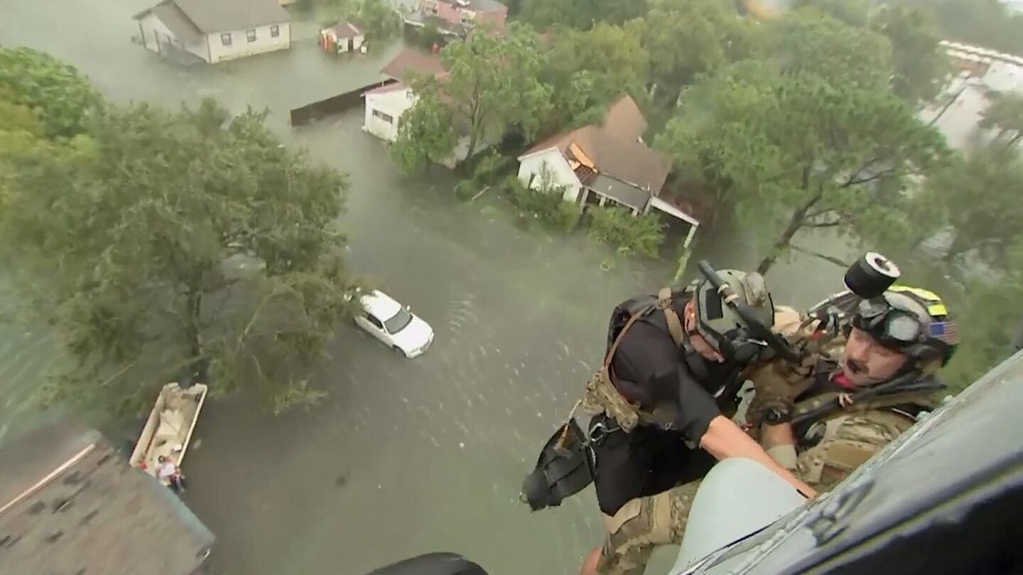 Two rescuers from US Navy Helicopter Sea Combat Squadron 7 are lowered to a house after Tropical Storm Harvey flooded a neighbourhood in Beaumont, Texas. Photograph: US Navy/Reuters