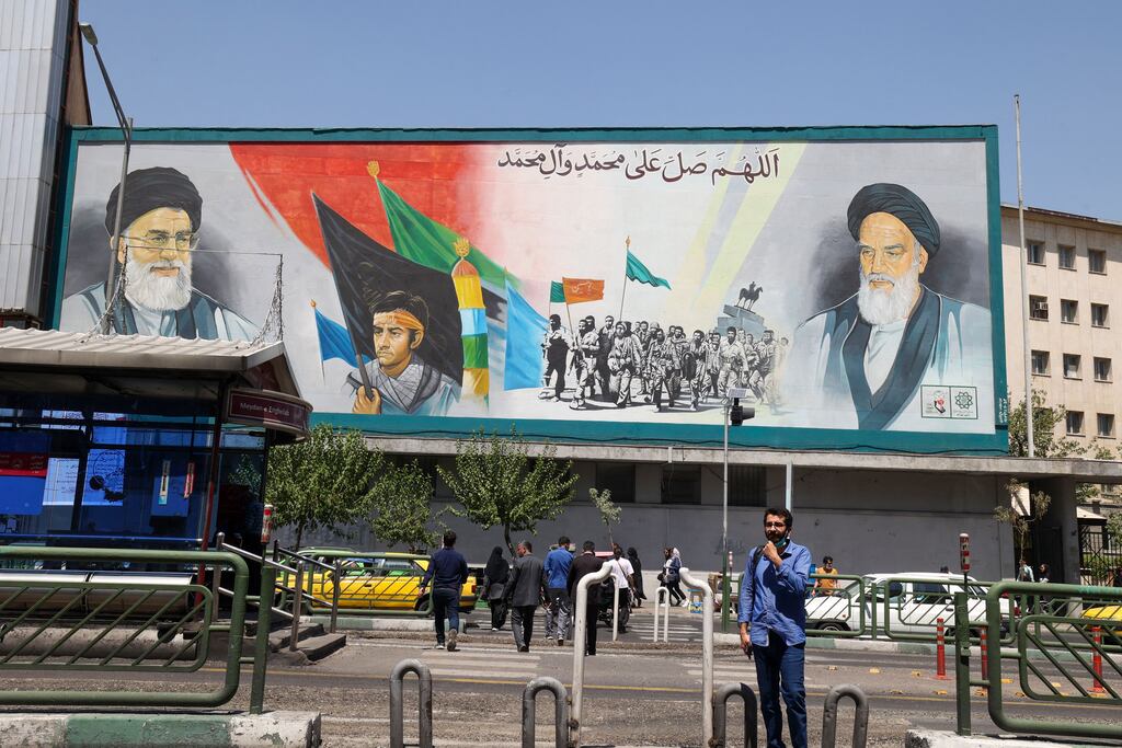 Iranians walk past a billboard bearing the portraits of Iran's Supreme Leader Ayatollah Ali Khamenei (L) and late supreme leader Ayatollah Ruhollah Khomeini in the capital Tehran on Saturday. Photograph: Atta Kenare/AFP/via Getty Images