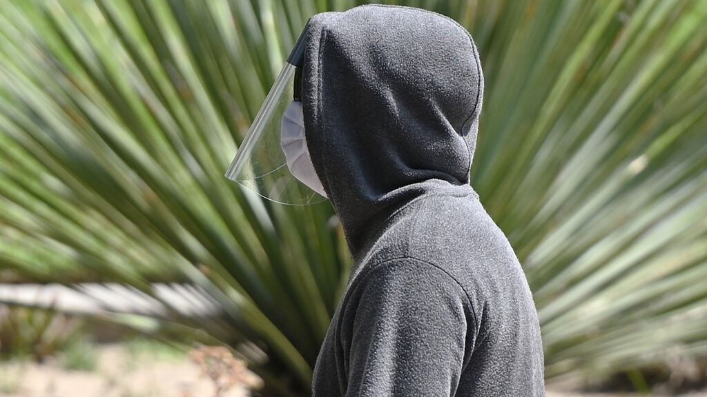 A man wearing a facemask and face shield walks in a downtown park in California. Photograph: Robyn Beck/AFP via Getty