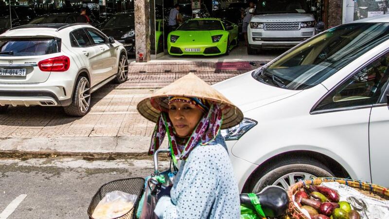 A woman passes a luxury car dealership in Ho Chi Minh City, Vietnam. Photograph: Christian Berg/New York Times