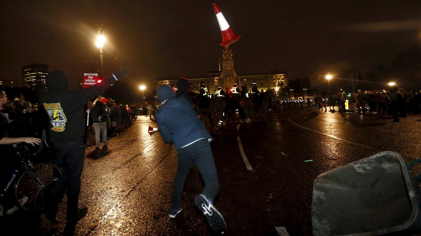 A supporter of the activist group Anonymous throws a traffic cone towards police officers outside Buckingham Palace during a protest in London. Photograph: Reuters