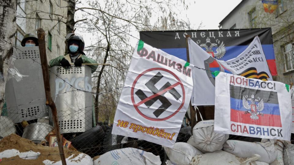 Pro-Russian protesters stand on a barricade with a poster reading: ‘Fascism will not go!’ in front of an occupied police station, in Slaviansk, Ukraine. Photograph: Anastasia Vlasova/EPA
