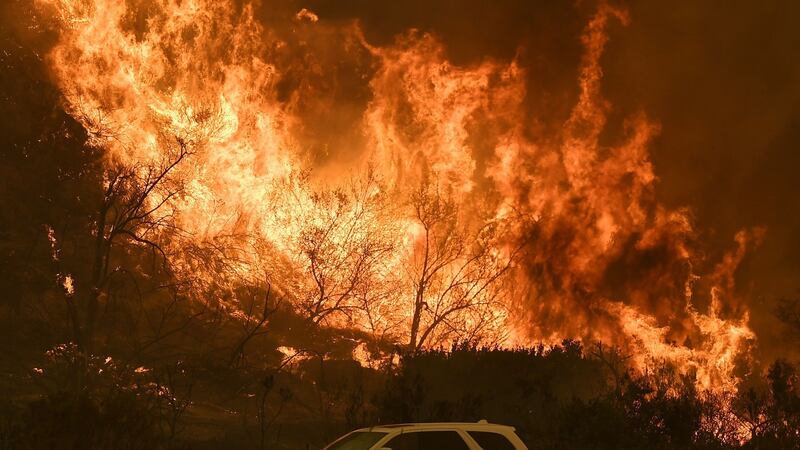 Vehicles pass beside a wall of flames on the 101 highway as it reaches the coast during the Thomas wildfire near Ventura, California on December 6, 2017. Photograph: MARK RALSTON/AFP/Getty Images