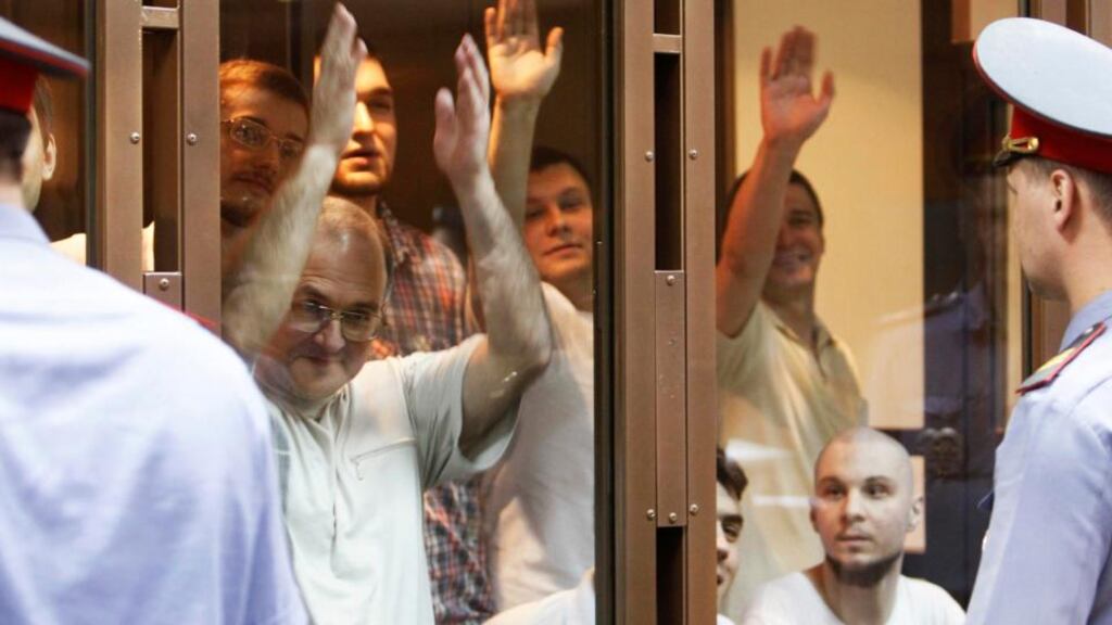 Defendants facing trial over clashes with the police during an anti-Putin protest last year, gesture inside a glass-walled cage before a court hearing in Moscow yesterday. Photograph: Sergei Karpukhin/Reuters