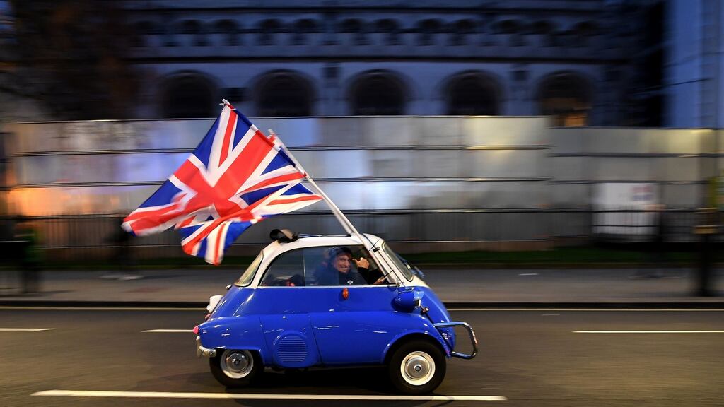 A man driving a BMW Isetta  drives past Brexit supporters gathering in Parliament Square, in central London on January 31, 2020, the day that the UK formally leaves the European Union. Photograph: AFP via Getty