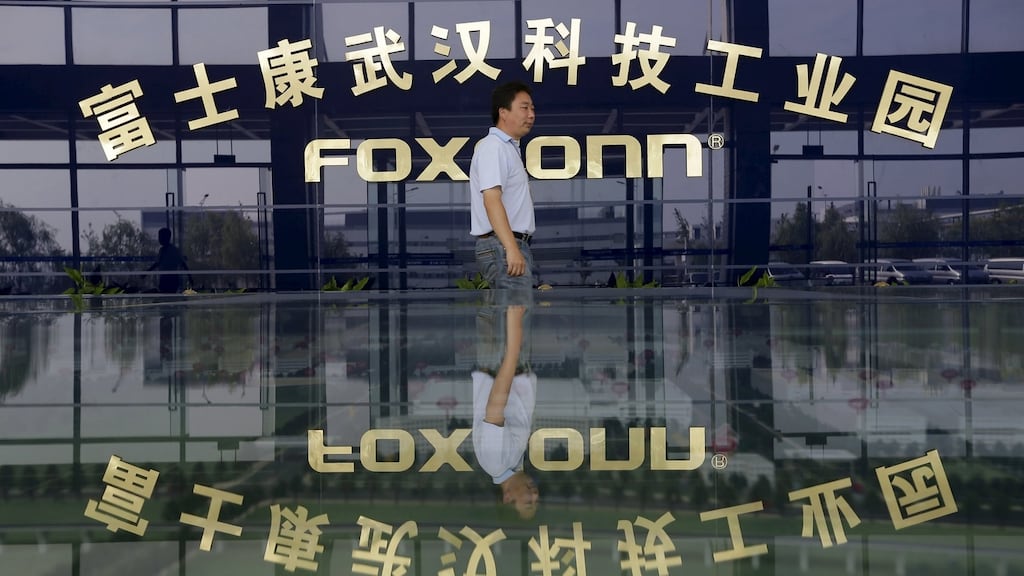 A man walks past a logo of a Foxconn factory in Wuhan, Hubei province