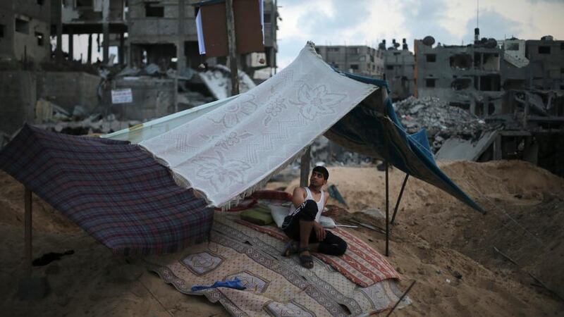 A Palestinian sits under a tent next to houses that witnesses said were heavy shelled by Israel during the offensive, in the Shejaia neighbourhood east of Gaza City yesterday. Photograph: Suhaib Salem/Reuters