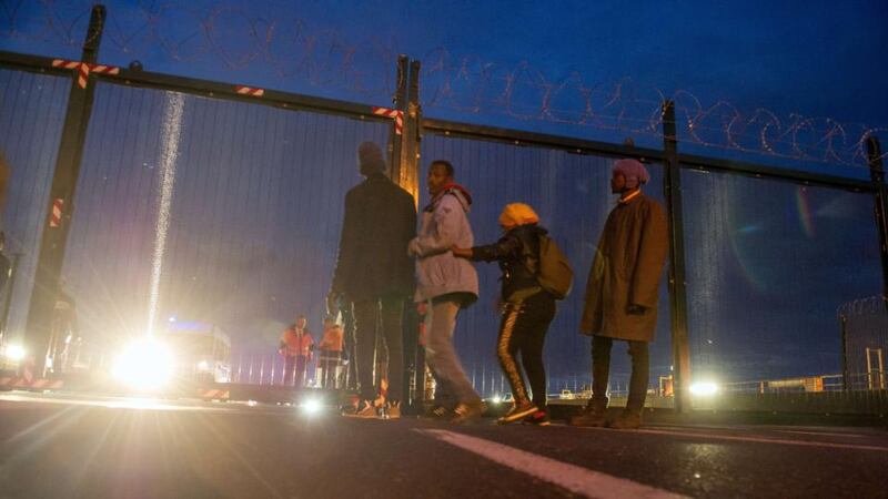 Migrants stand in front of a fence on the Eurotunnel site near the boarding docks in Coquelles near Calais, northern France, on Wednesday. Photograph: AFP
