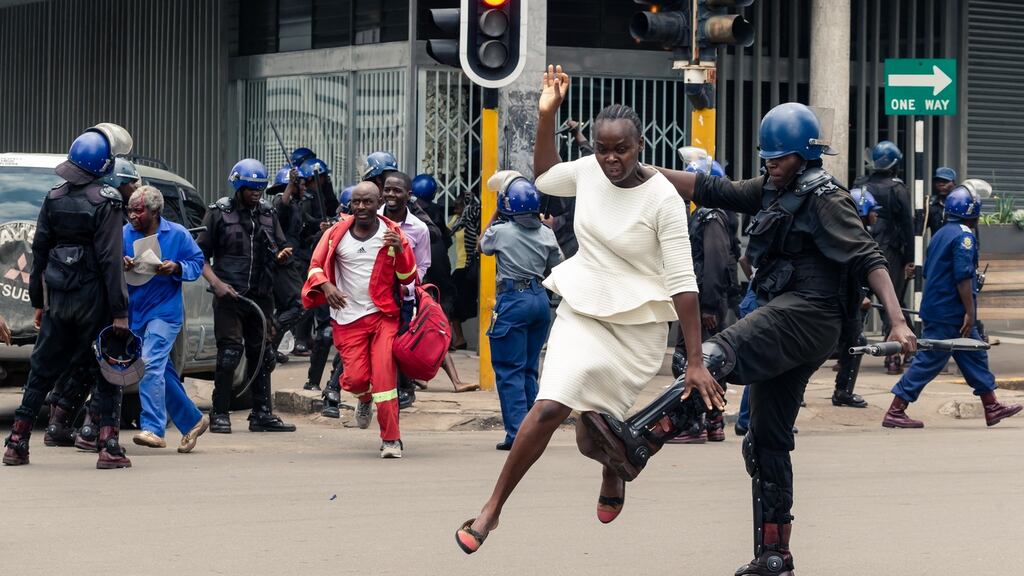 An anti-riot policeman in Zimbabwe tackles a woman as police disperse a crowd gathered to hear an address by MDC Alliance Nelson Chamisa in Harare. Photograph: Jekesai Njikizana/AFP