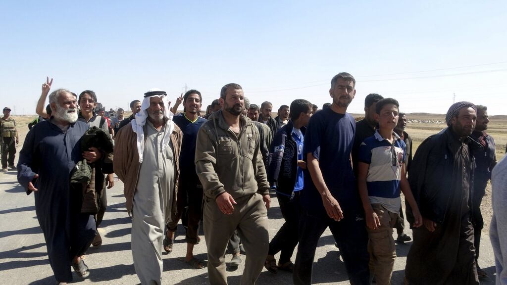 Civilians who fled their homes due to the clashes between Iraqi security forces and Islamic state militants move through the town of Hit in Anbar province