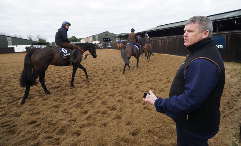 Gordon Elliott looks on as Delta Work ridden by Darren Treacy goes out on the gallops.